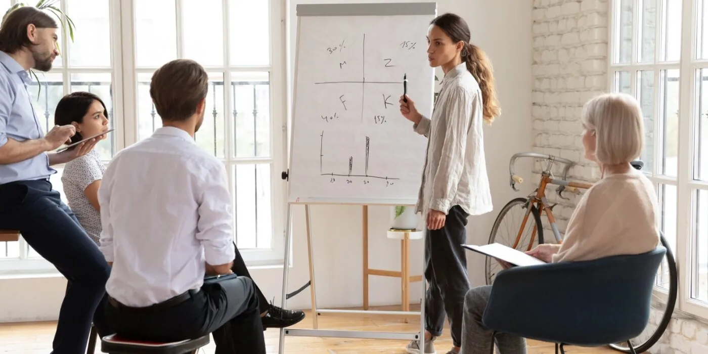 Group of colleagues discussing top on white board