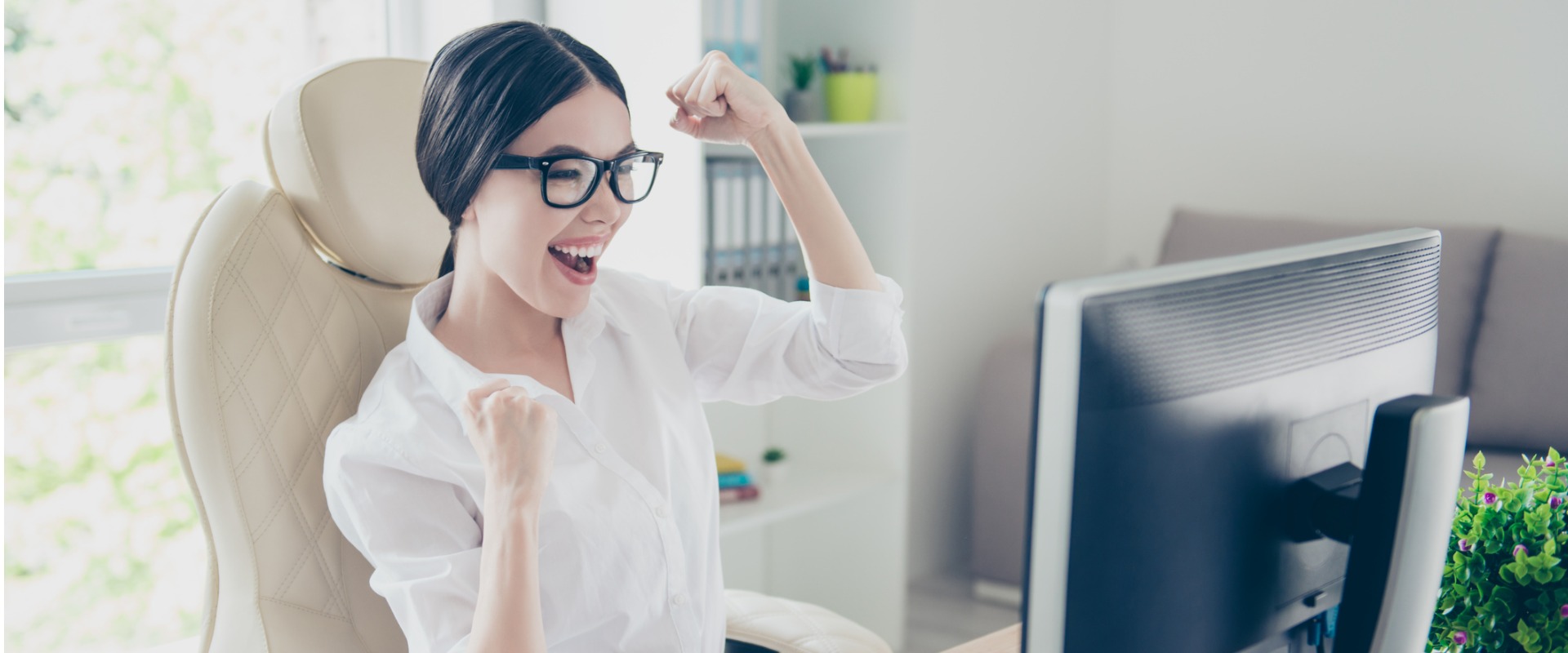 Cheerful woman celebrating at computer