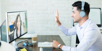 man waving to colleague on video conference