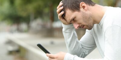 sad adult man checking bad news on smart phone