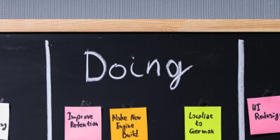 Header image of a blackboard divided into typical sprint sessions with sticky notes: To Do, Doing, Done