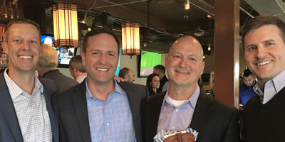 Jason Hansen, Kirk Mielenz, Michael Turner, and Robert Sunker smile for the camera at a party.