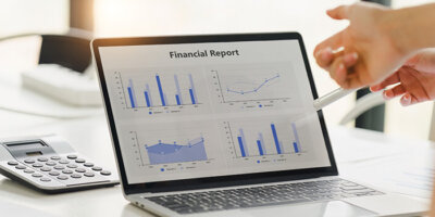 Two colleagues analyzing financial data reports on laptop with charts and graphs at modern office