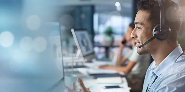 A man in a call center answers an incoming customer call while looking at his screen.