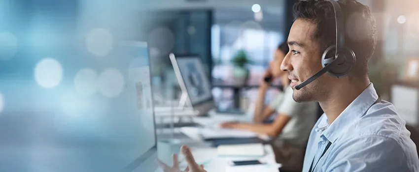 A man in a call center answers an incoming customer call while looking at his screen.