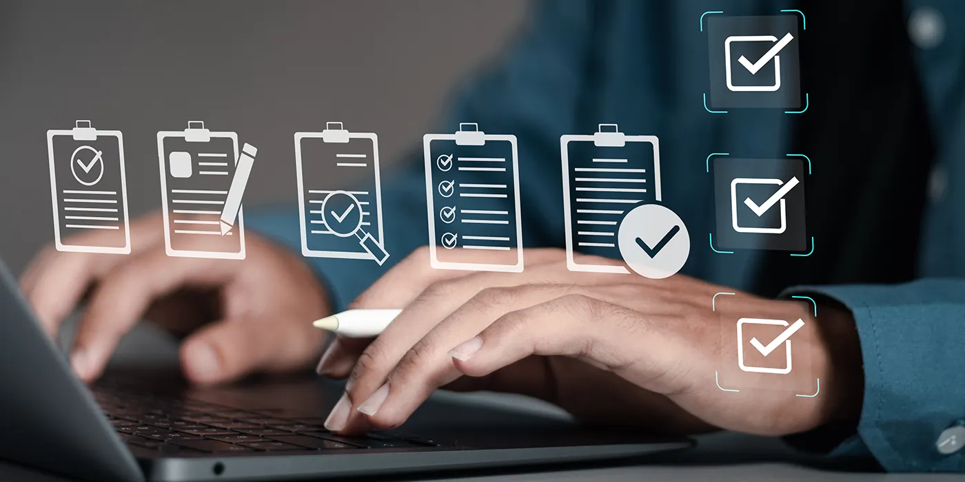 A person types on a laptop. Above the laptop hovers icons of various checklists, representing data quality controls.