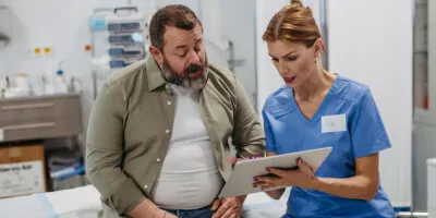 A female doctor uses a tablet to discuss medical care with her patient